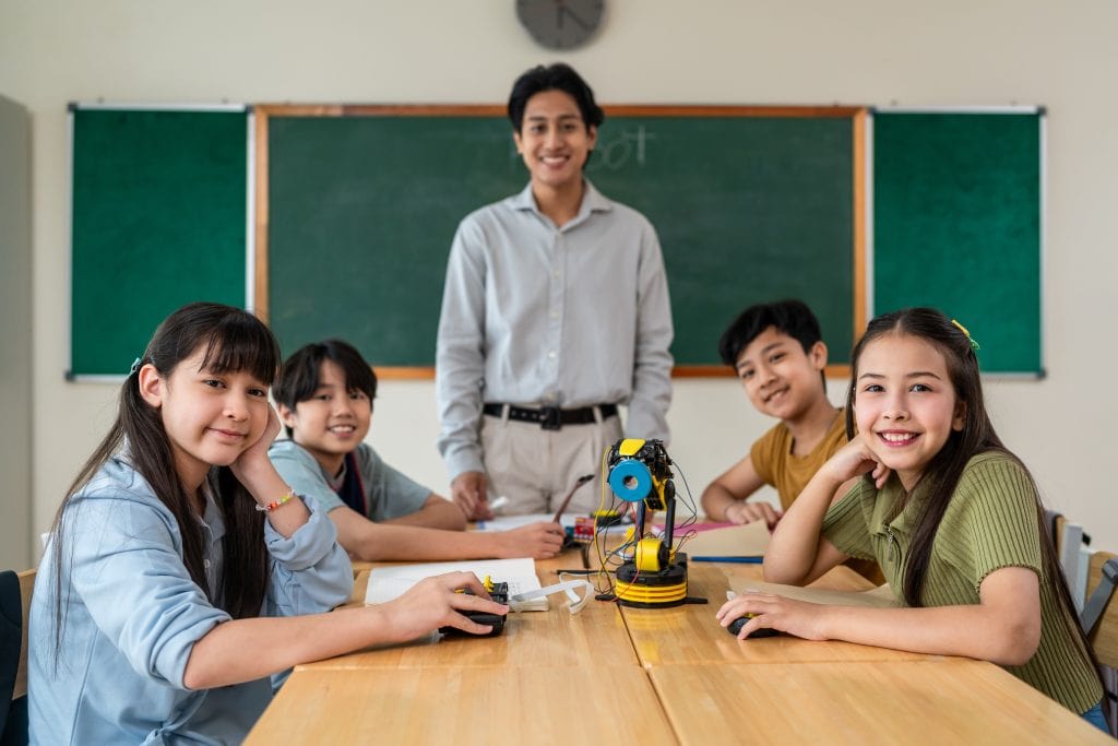 Innovative classroom with children engaging in robotics and STEM activities, led by a teacher, promoting technology education and fostering creativity in students.